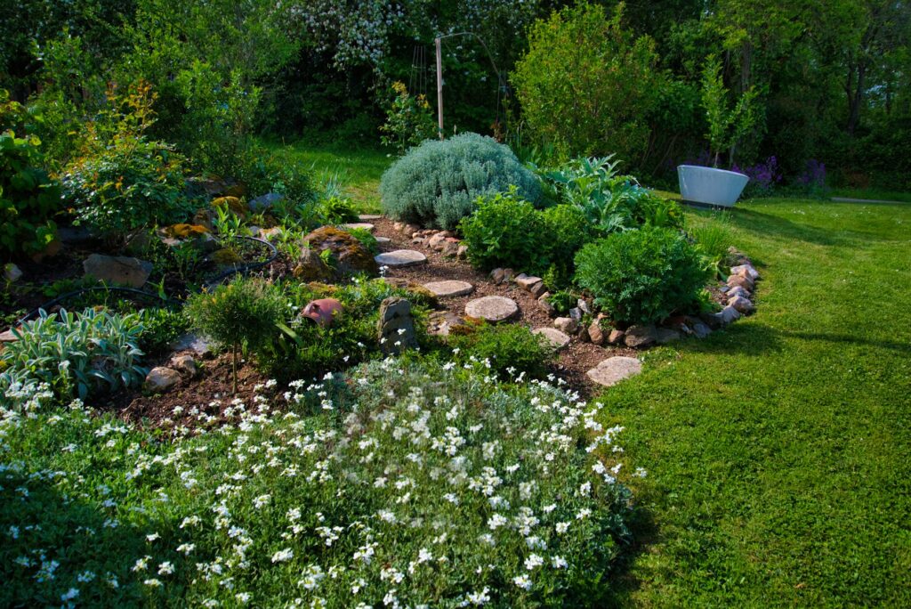 Jardín con césped, arriates de flores y camino de piedra